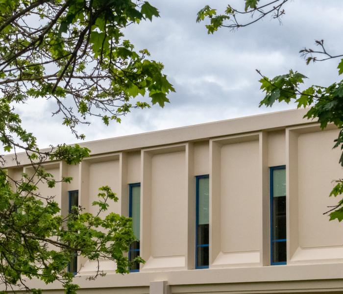 Exterior photo of Salazar Hall with green trees in the foreground